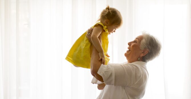 Older woman holding you girl in air